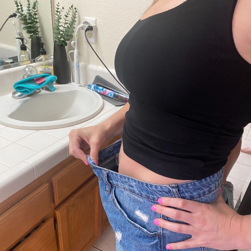 Image of a client showing weight loss by showing how big her shorts are now, she is holding the front of the shorts