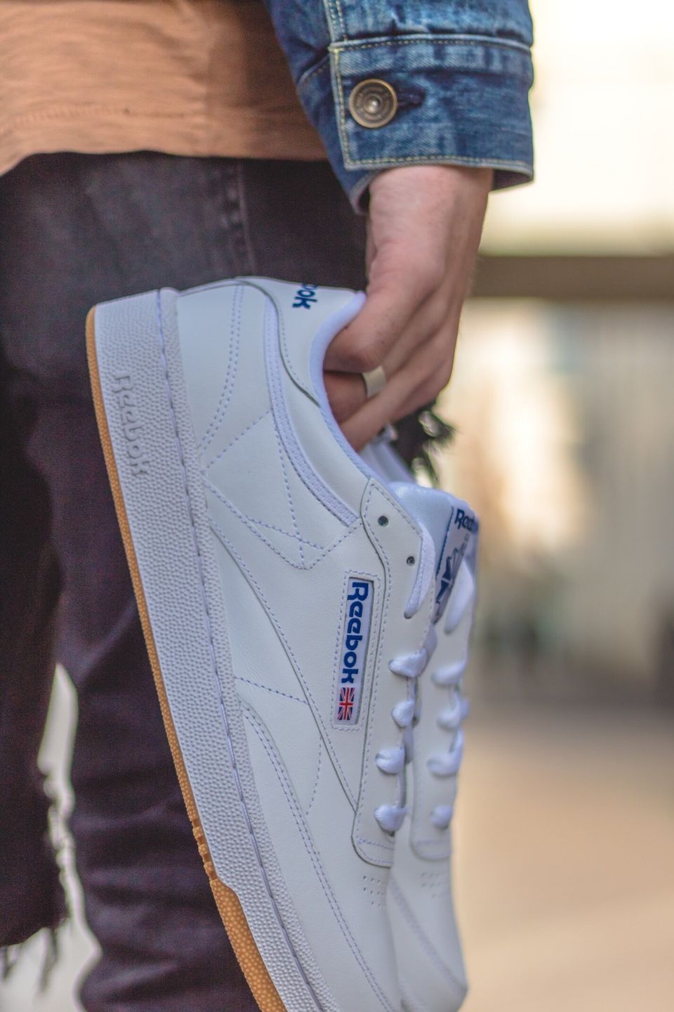 Someone holding some old school white Reeboks - photo focused in on the shoes 