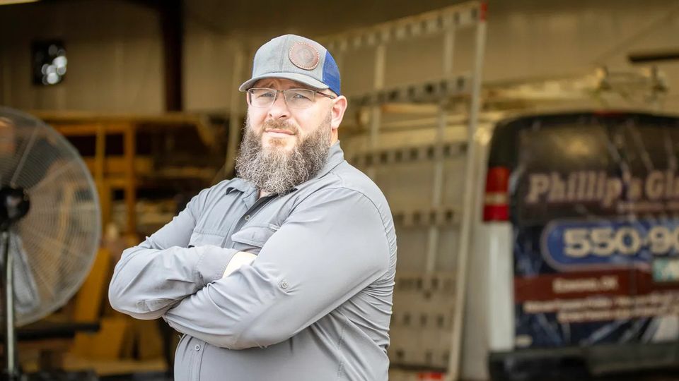 Phillip’s Glass professional standing with arms crossed inside the workshop