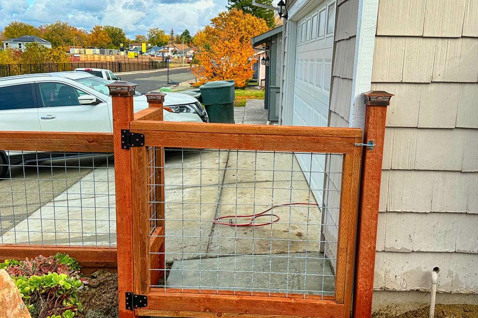 Wood and wire mesh gate installed beside residential garage on concrete walkway