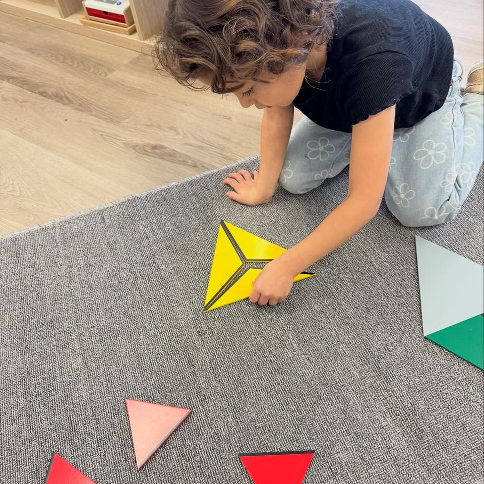 Preschool boy arranging Montessori constructive triangles on a work rug during a shape lesson in Palmdale CA