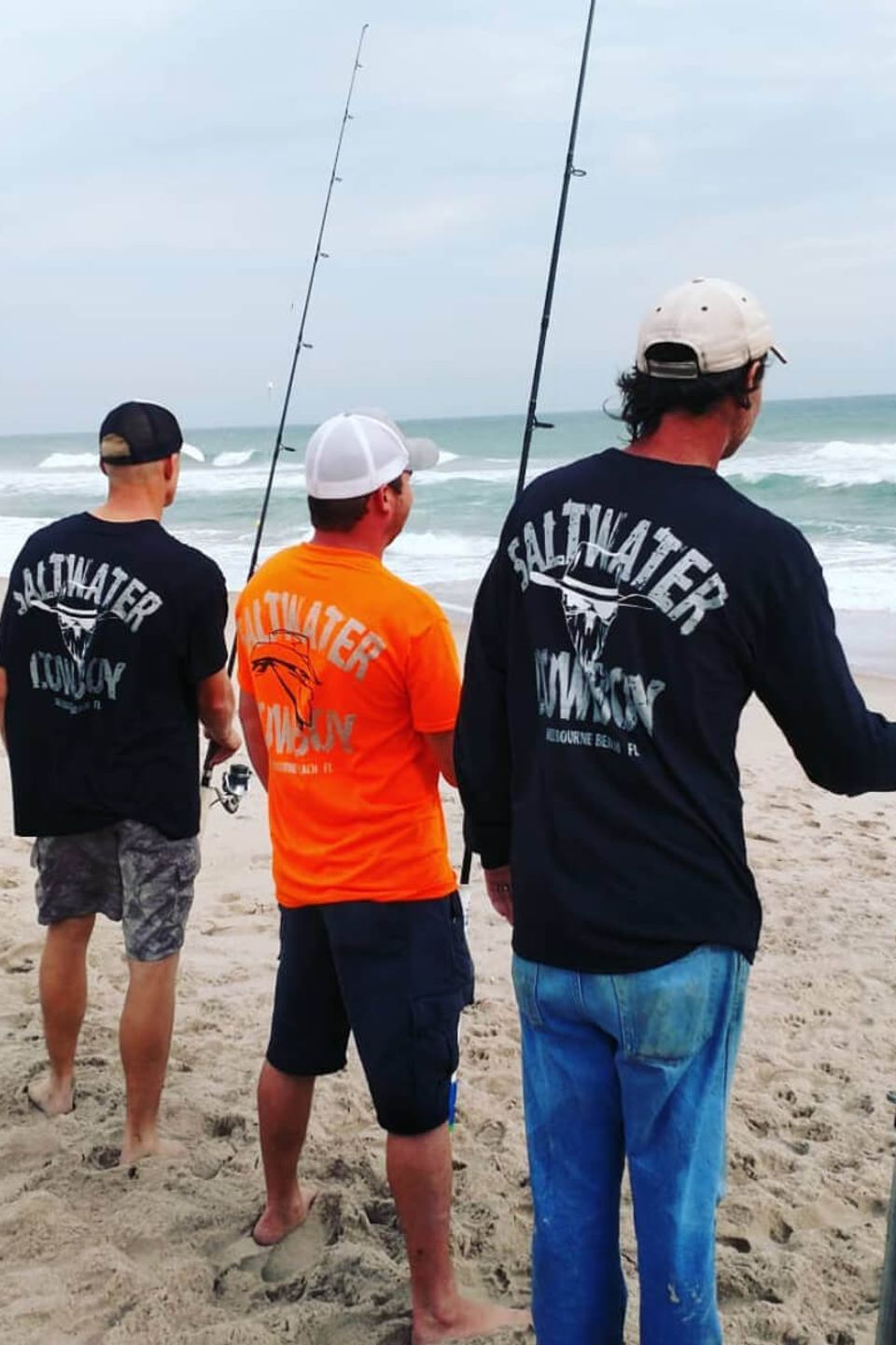 Fishermen holding rods and reels on the beach