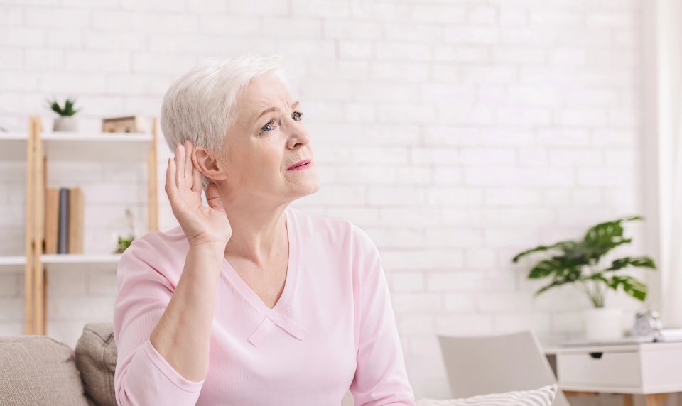 Age-related hearing loss, symptoms. Senior woman listening for something at home