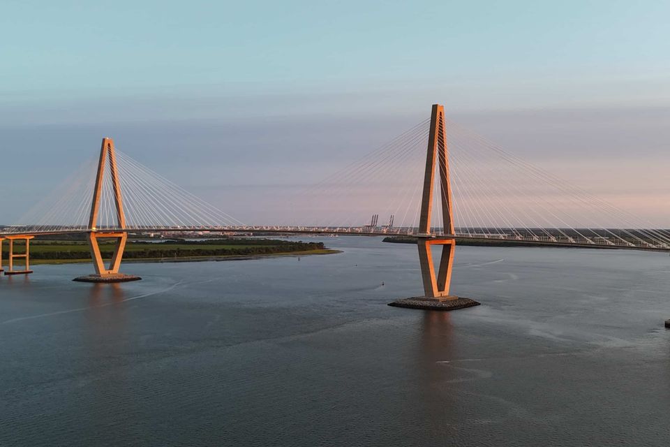 Arthur Ravenel Jr. Bridge at sunset spanning the Charleston Harbor with calm water and pastel skies