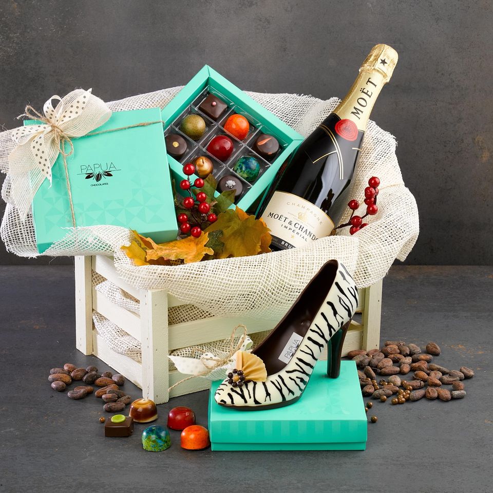Gift crate with Moët champagne, assorted chocolates, zebra-print shoe, jars of treats, and decorative berries and leaves Chocolate