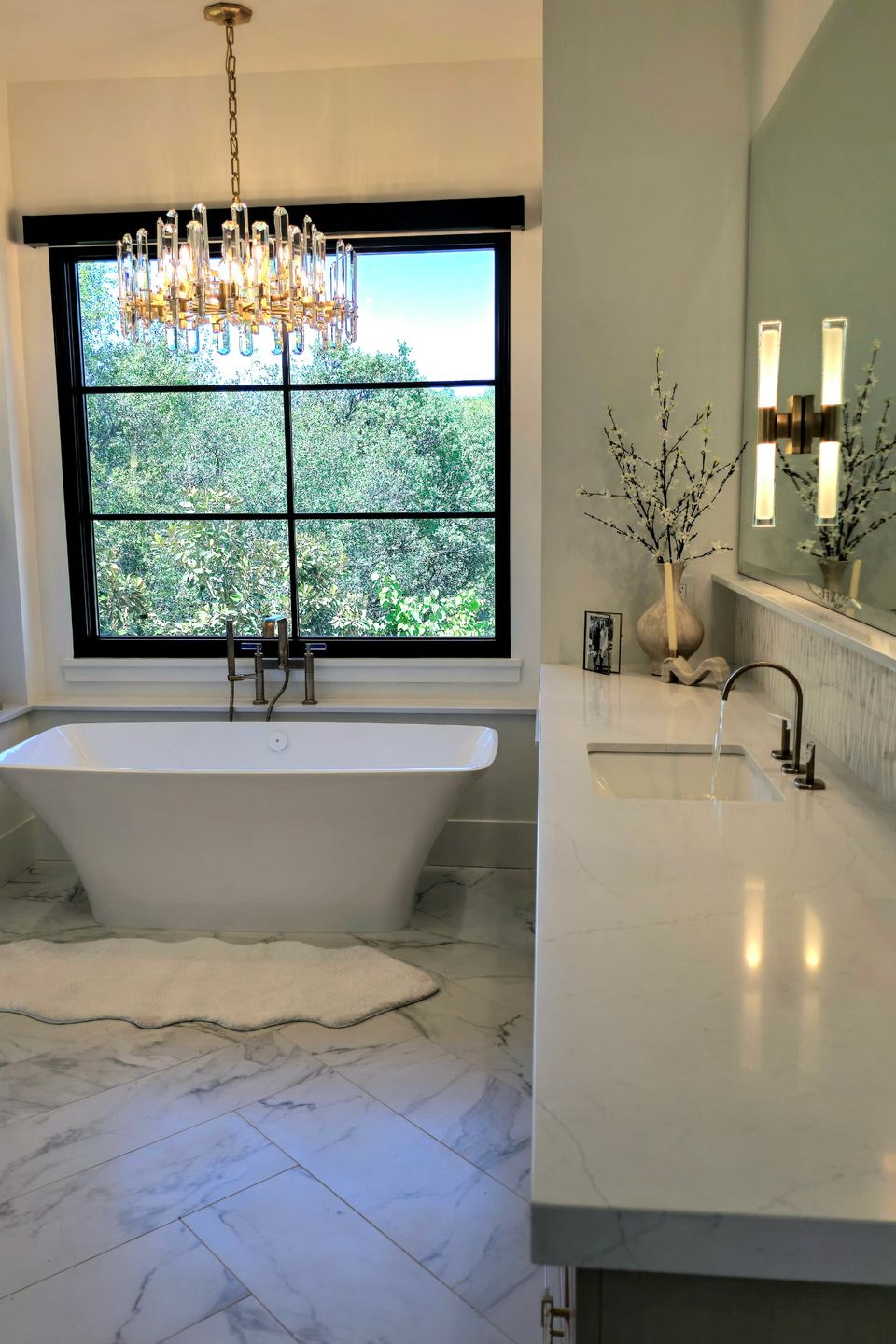 Luxury master bathroom featuring a freestanding soaking tub, white marble-patterned porcelain floor tiles in a herringbone layout, and a custom quartz vanity countertop—Artisan tile installation and stone fabrication by LuXe Design Tile and Granite inc.