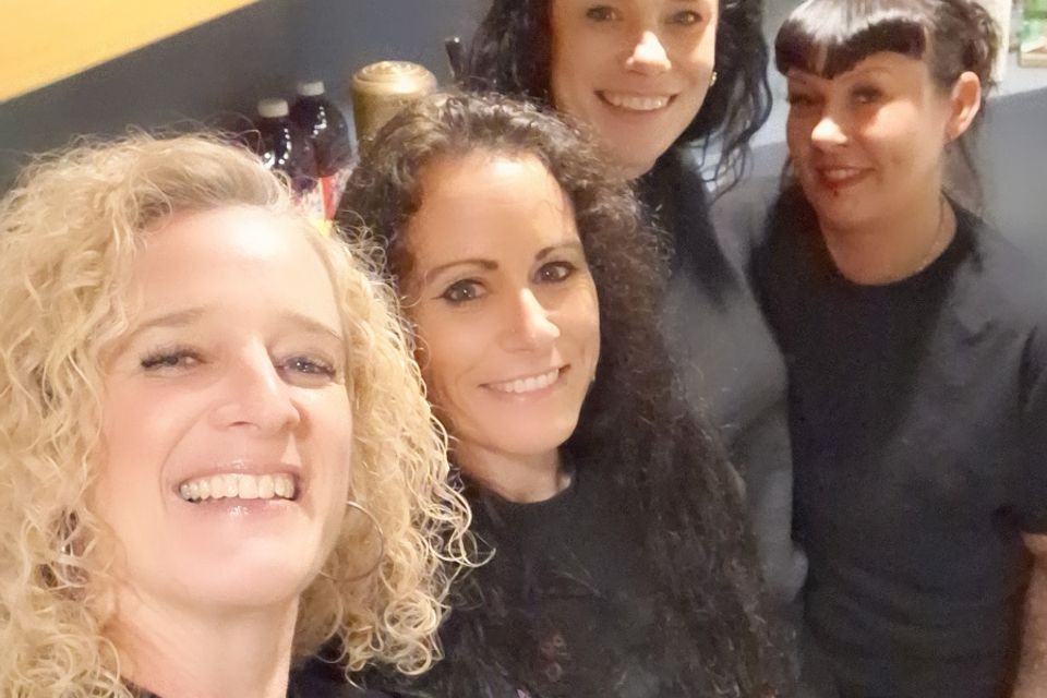Group of bartenders posing together behind a bar setup at an event