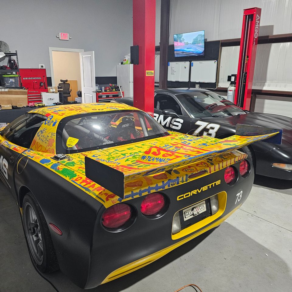 Bennett Motorsports Support enclosed race car trailer with official BMS branding and website URL parked at a race track paddock
