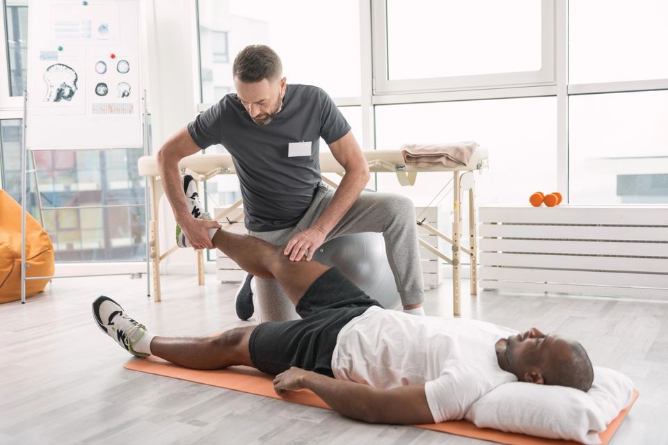Physical therapist treating a patient's leg injury during a sports rehabilitation session