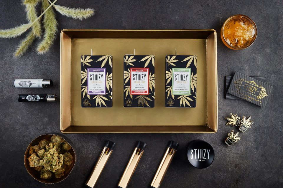Stiiizy vape pods in a box with marijuana, vape pen battery, stickers, and resin.