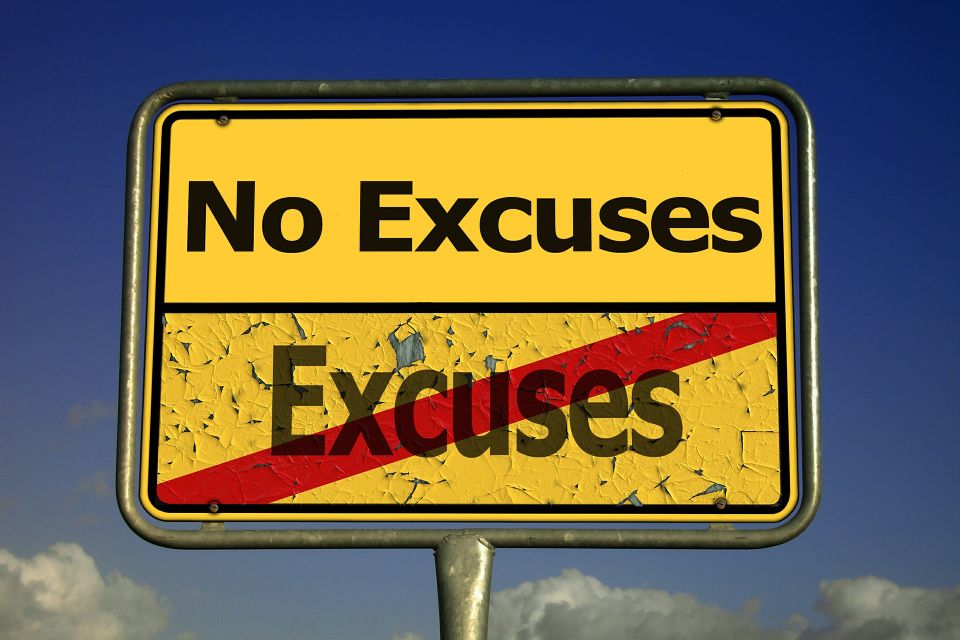 A yellow road sign with the text 'No Excuses' at the top and the word 'Excuses' crossed out in red below, set against a clear blue sky background.