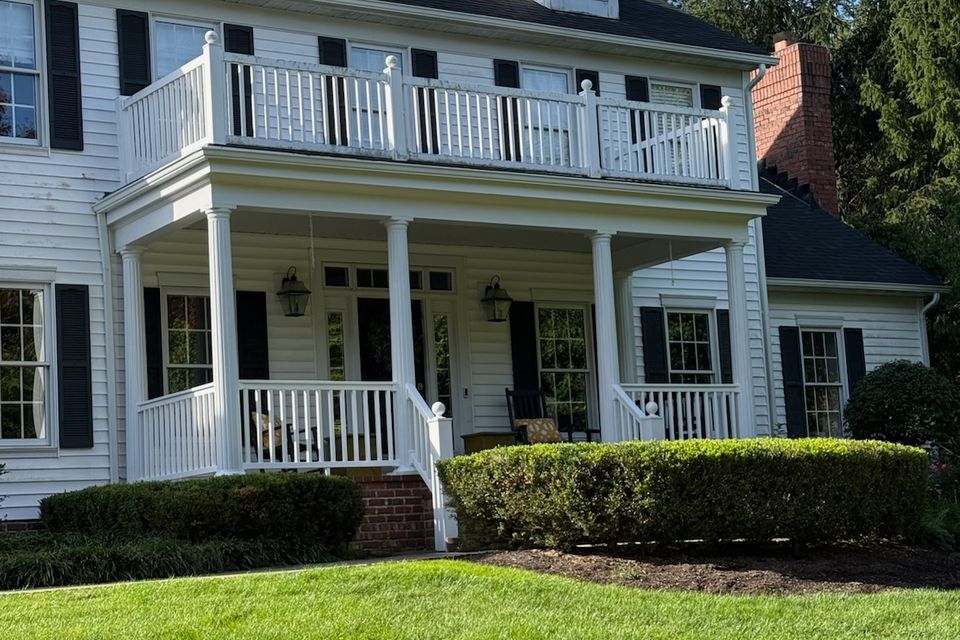 White colonial home with covered front porch and second-storey balcony remodeled on Cleveland's east side