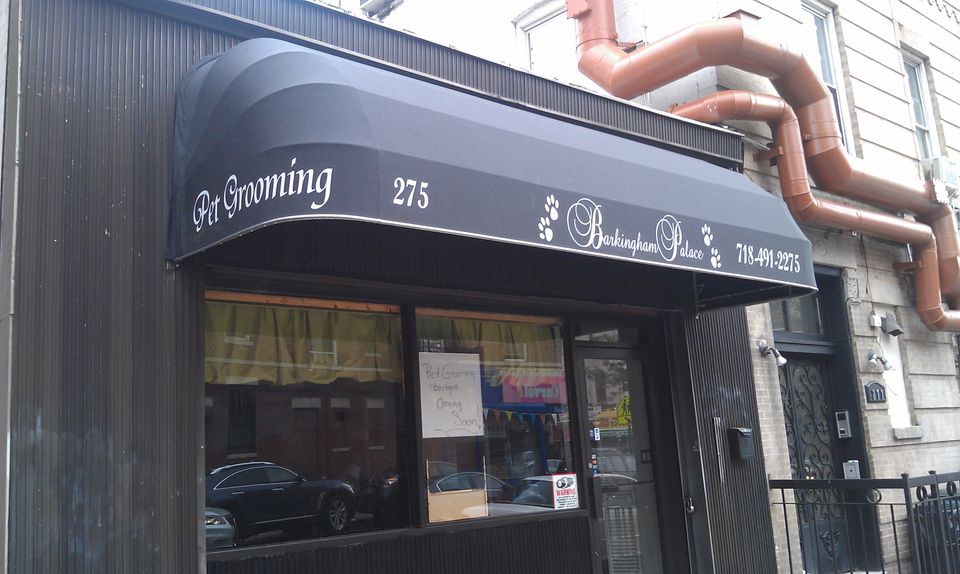 Black storefront awning with white script lettering and a shaped valance on a Brooklyn pet grooming shop