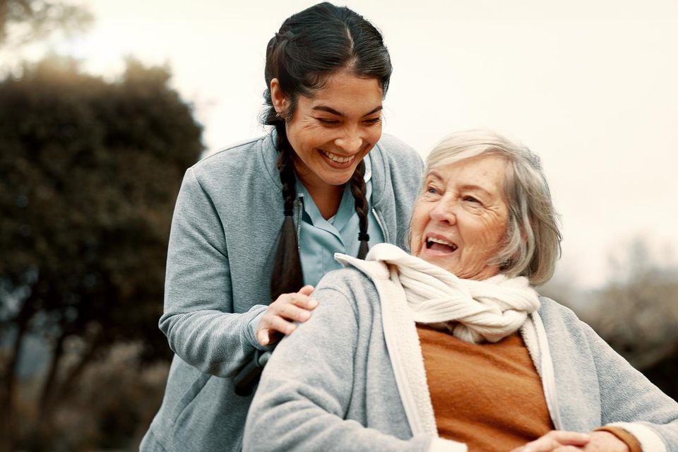 Caregiver sharing a laugh with senior woman outdoors during companion care in Long Island NY
