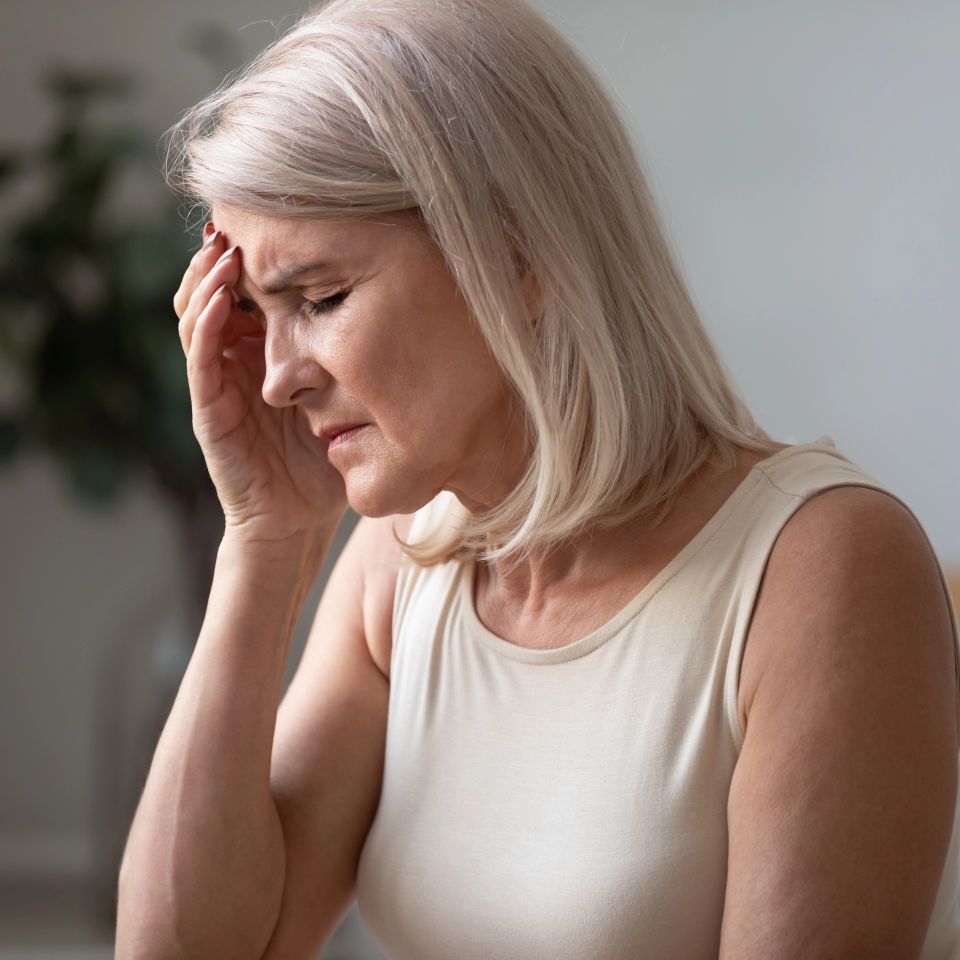 A close up shot of an unhealthy woman touching her head, suffering from chronic fatigue