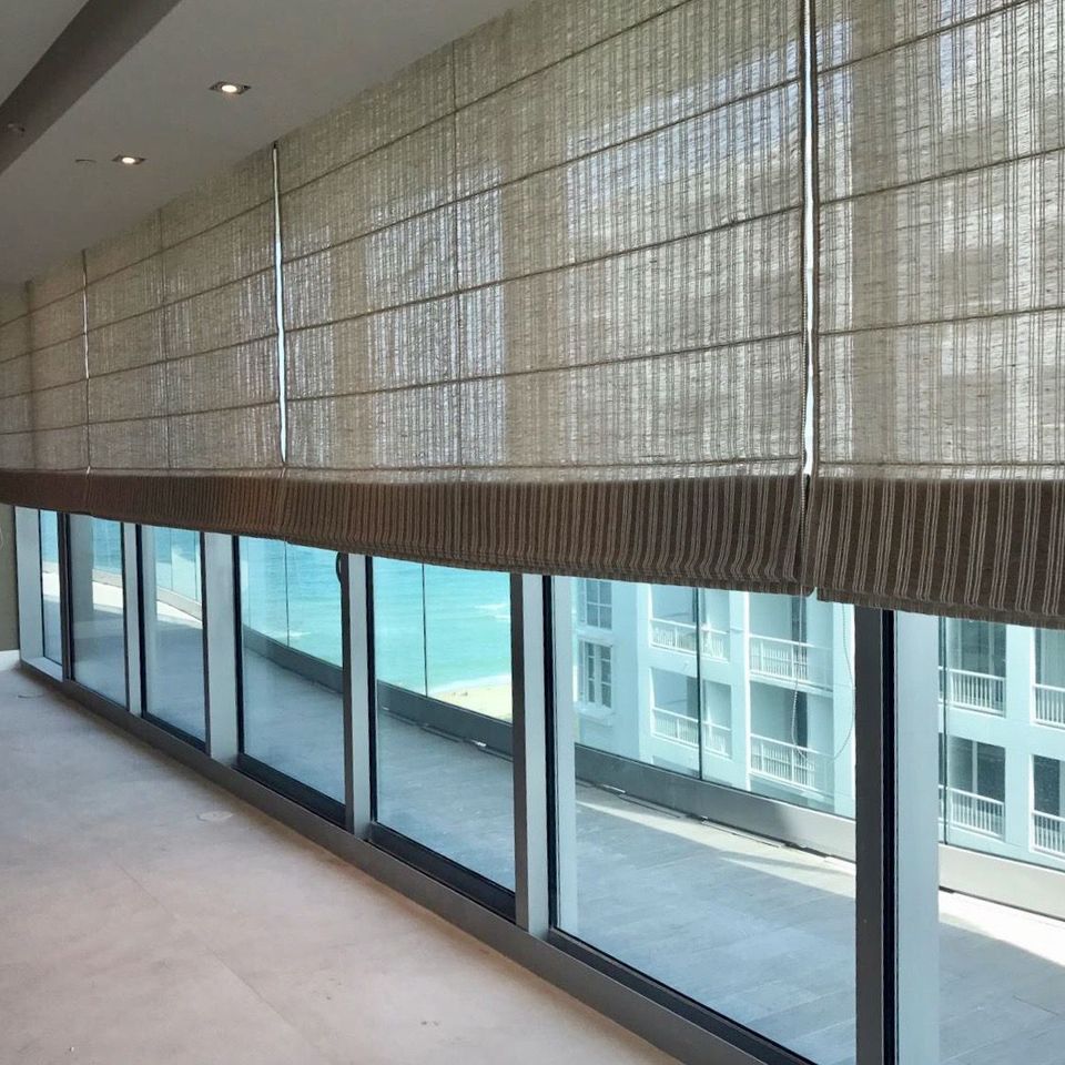 Elegant Roman shades installed along a modern high-rise balcony with floor-to-ceiling windows