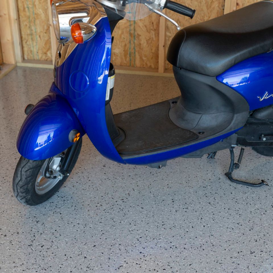 Blue scooter parked on EverStone Flakes flooring inside a garage.
