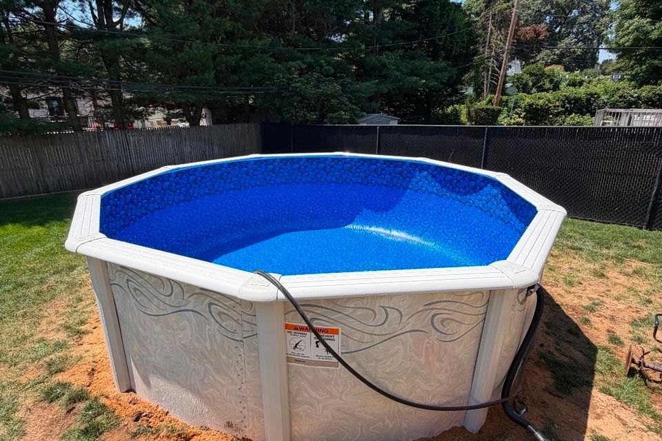 Round above ground pool installation with new liner and sand base in a Long Island backyard