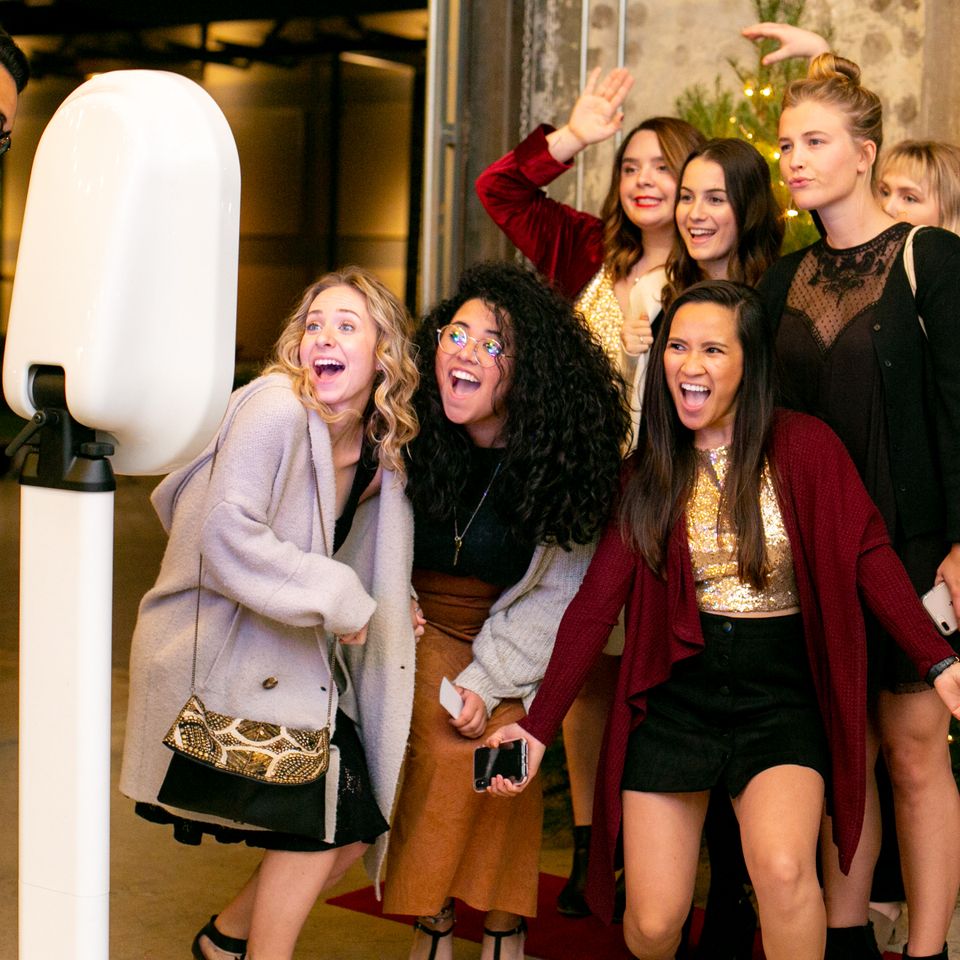 Party guests gathered around a digital photo booth, laughing and posing together