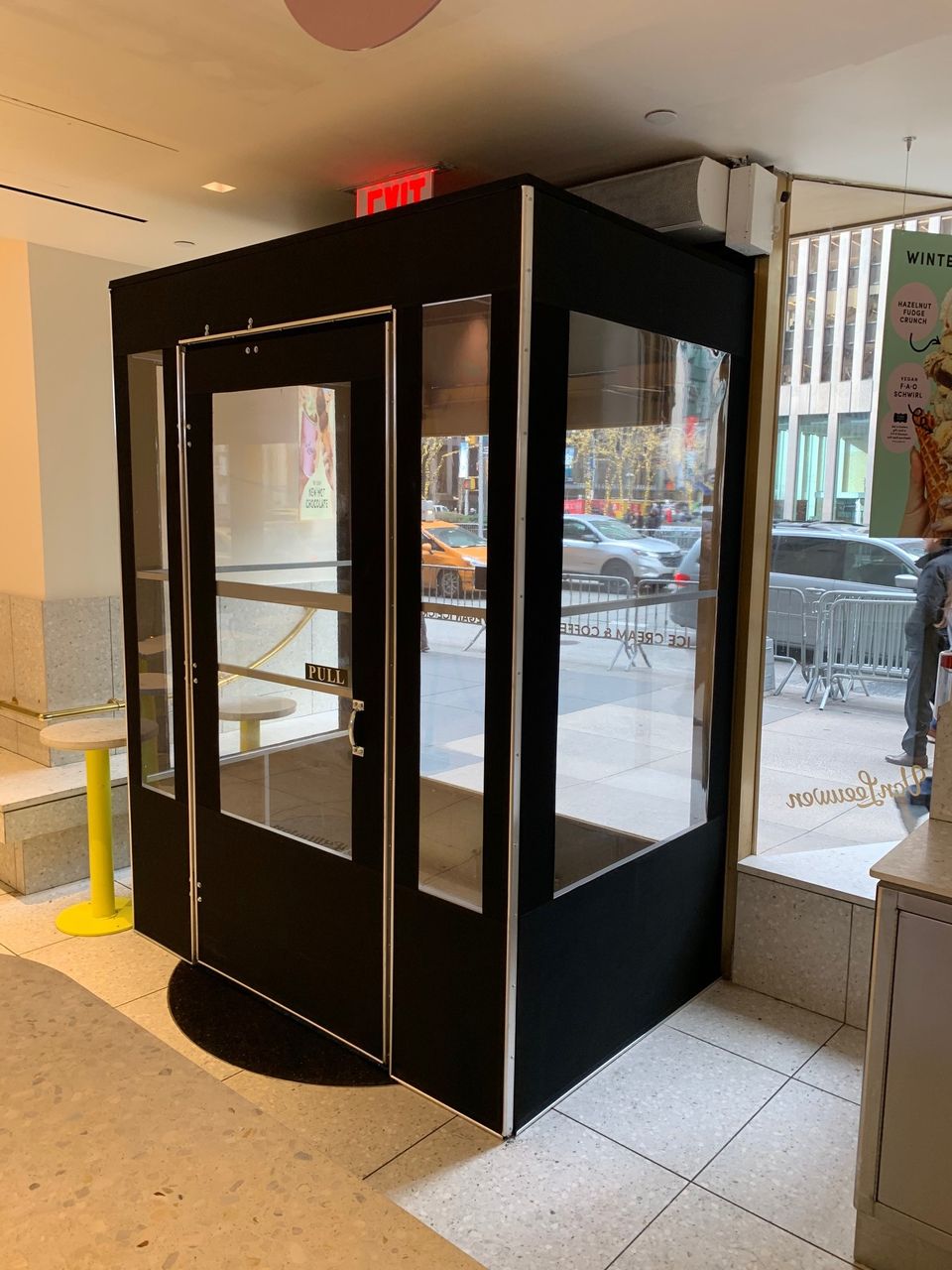 Black framed seasonal vestibule with clear vinyl panels inside a Midtown Manhattan storefront entrance