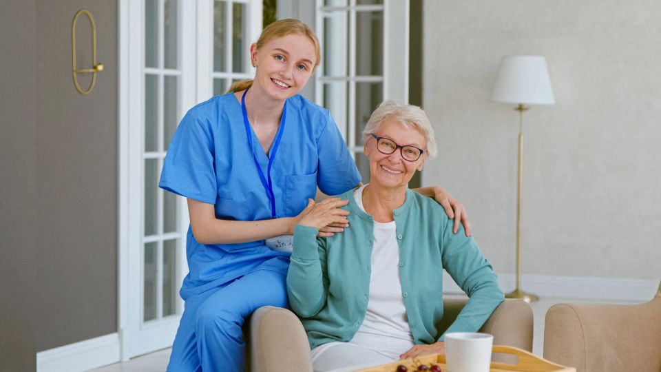 A elderly woman and her assisted living caretaker smiling