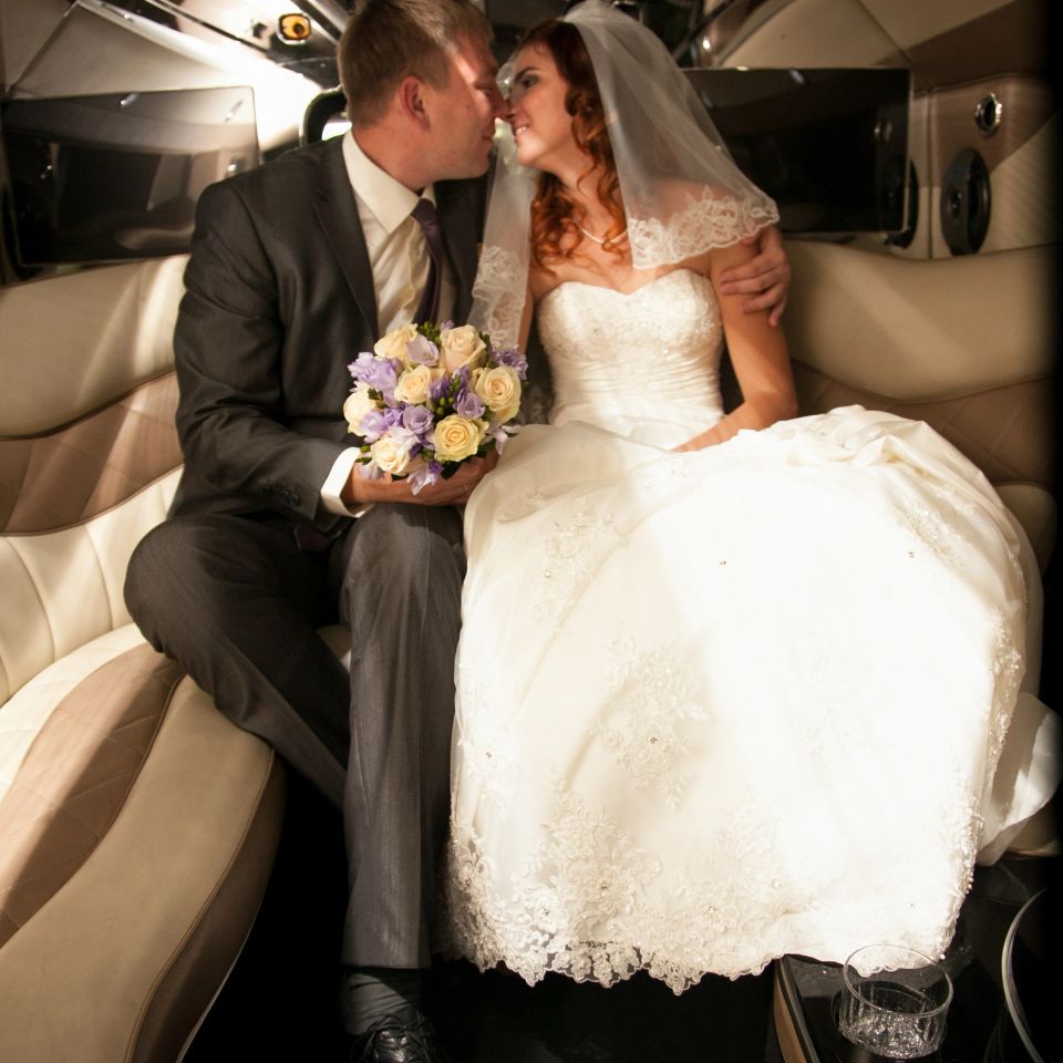 Beautiful newly married couple kissing on back seat of limousine