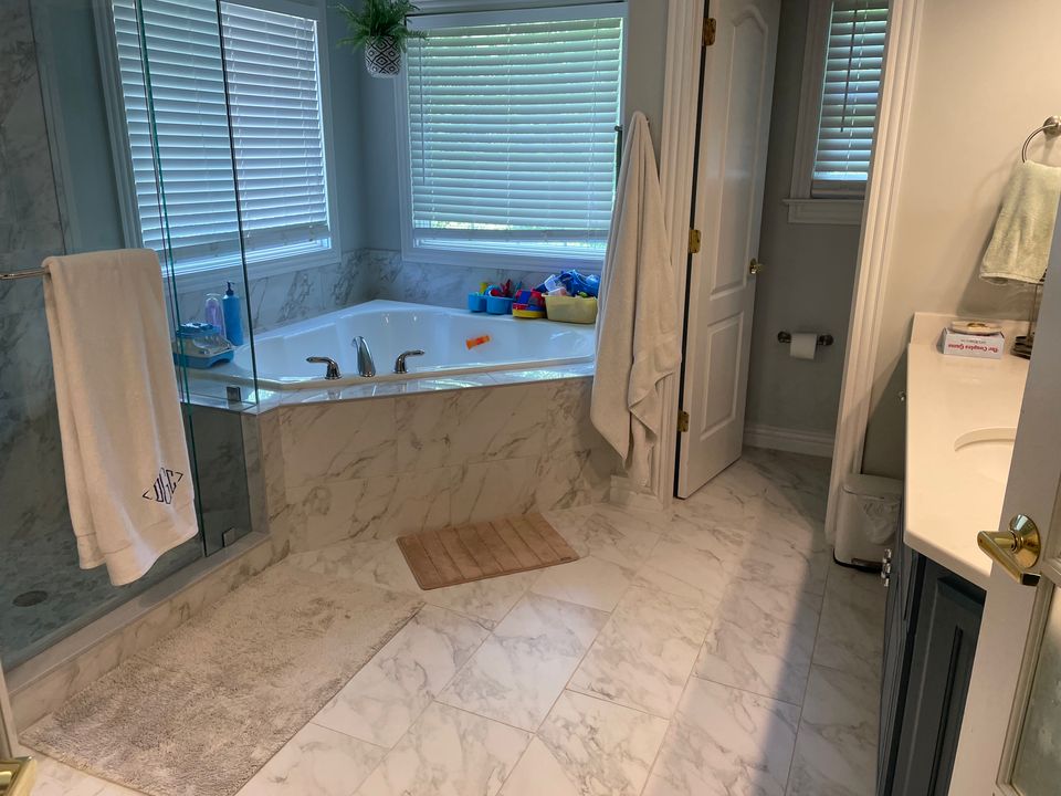 Spotless marble bathroom with corner tub and glass shower after a house cleaning service in Virginia Beach VA