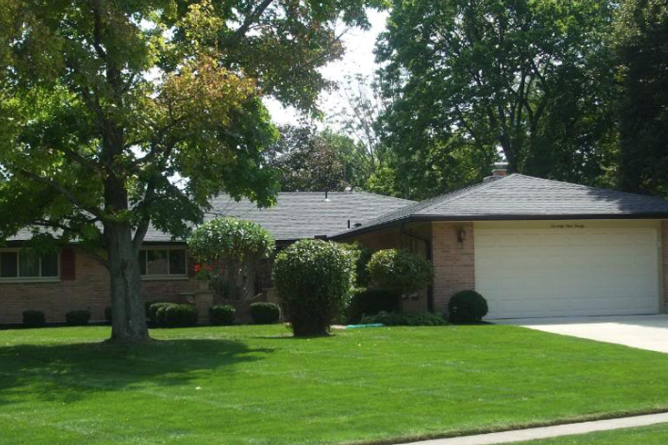 Single-story brick home with a professionally installed asphalt shingle roof by E & D Roofing, Inc.