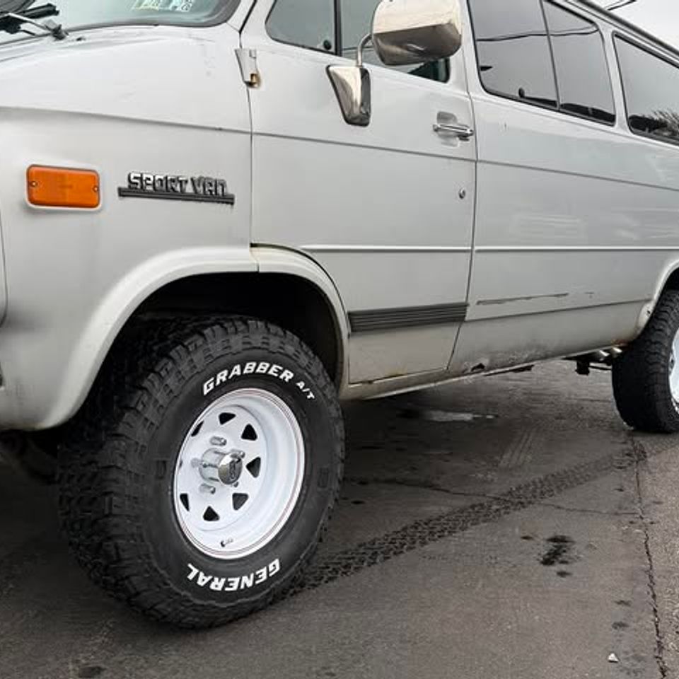 White Chevy Sport Van with new General Grabber off-road tires and white wheels in Claymont DE