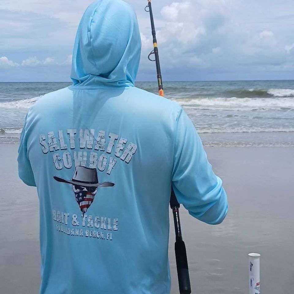 Man fishing on the beach wearing a Saltwater Cowboy sweatshirt