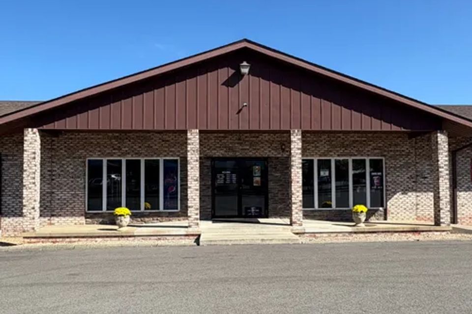 Front entrance of Cocca’s Pizza Boardman Ohio location with brick exterior, large windows, and planters by the doorway.