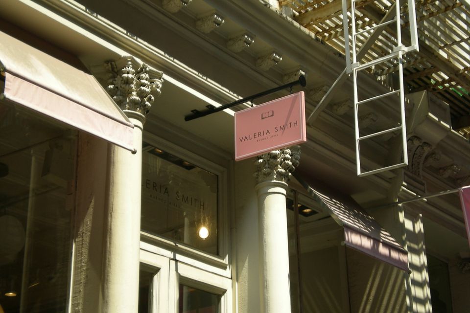 Pink pan-formed blade sign projecting from a cast-iron SoHo facade above a boutique entrance