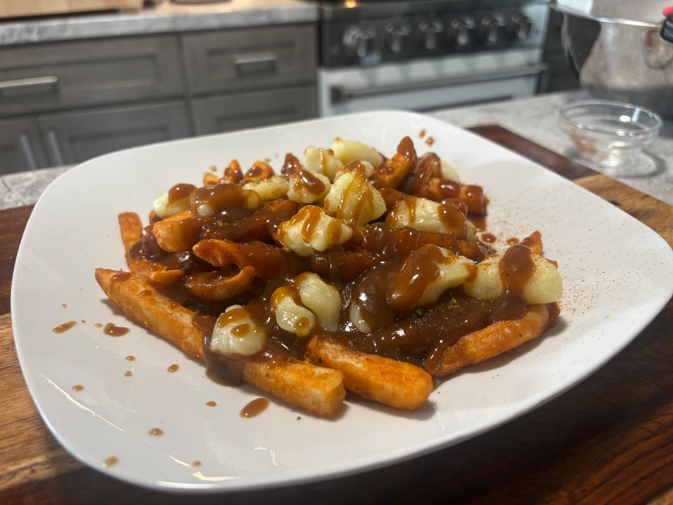 Poutine dish made with golden French fries, melted cheese curds, and brown gravy, presented by Besuretocook