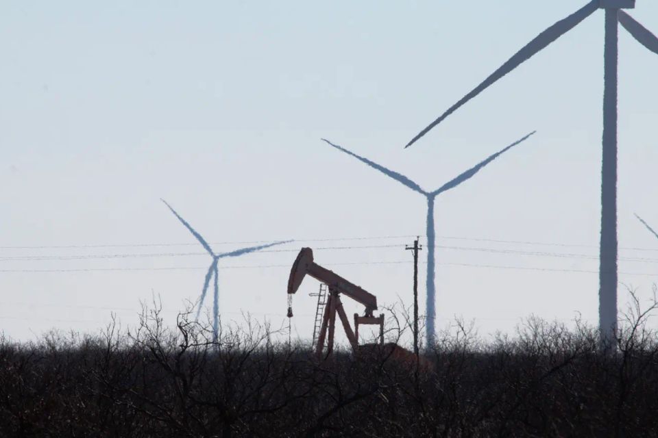 Outside ozona  an oil pumpjack works beneath a line of wind turbines(reid bader grist)