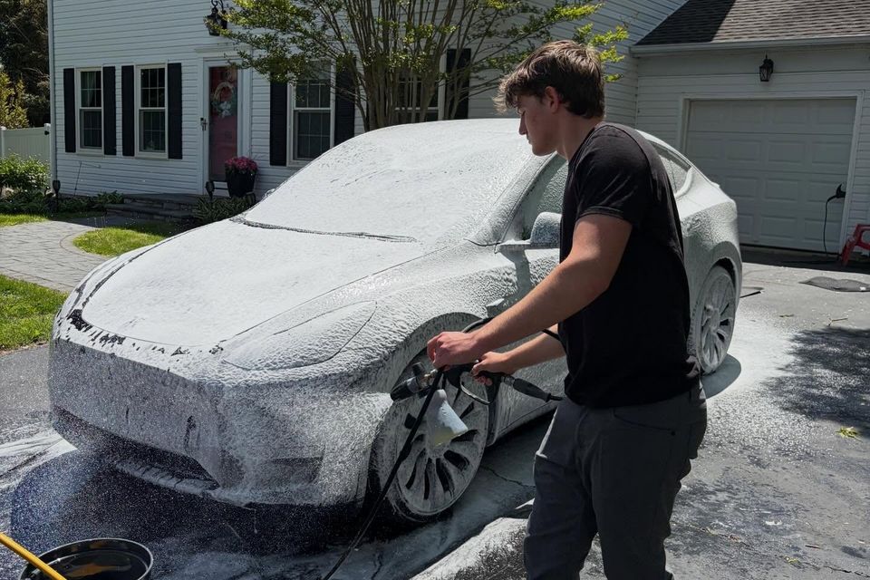 Detailer spraying thick snow foam onto a Tesla Model Y with a foam cannon during a mobile wash in Wilmington DE