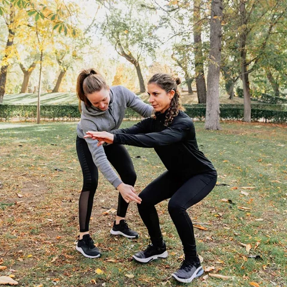 Personal trainer training squat outdoors exercising 1296x728 header