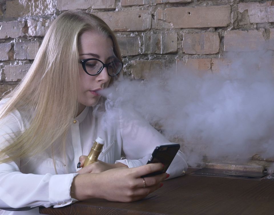Young girl smoking electronic cigarette and using smartphone sbi 351104015