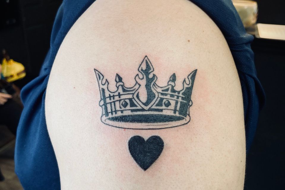 Image of a tattoo of a heart under a crown in black and grey