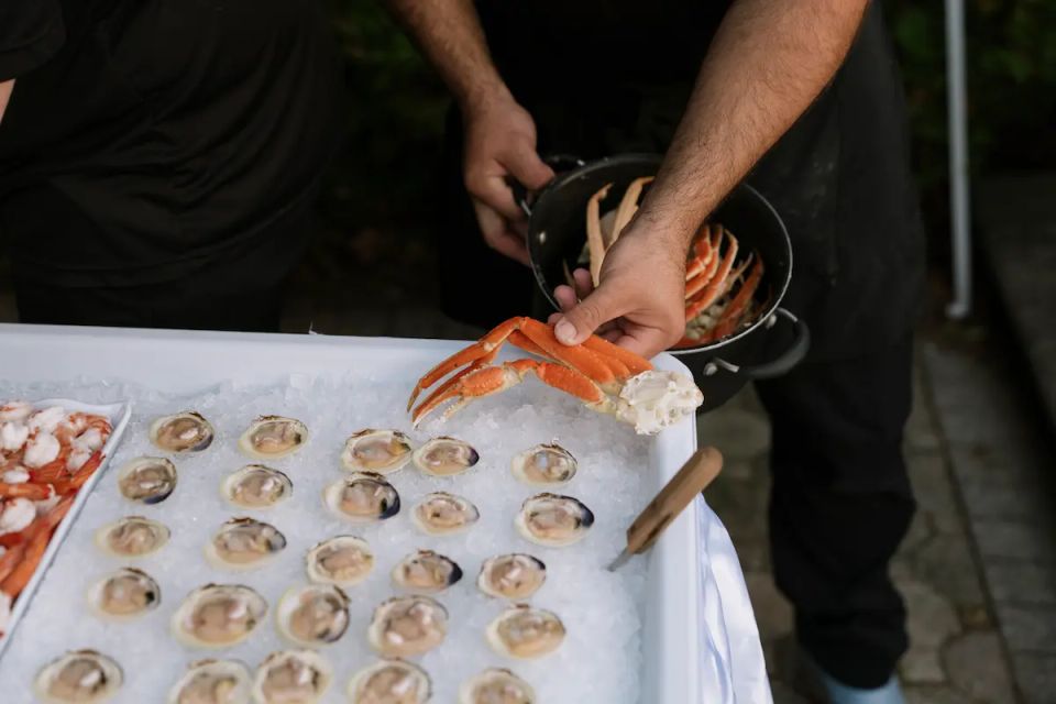 A man holding a crab leg, with clams, raw bar, provided by Shore2Shore Shucking of Long Island