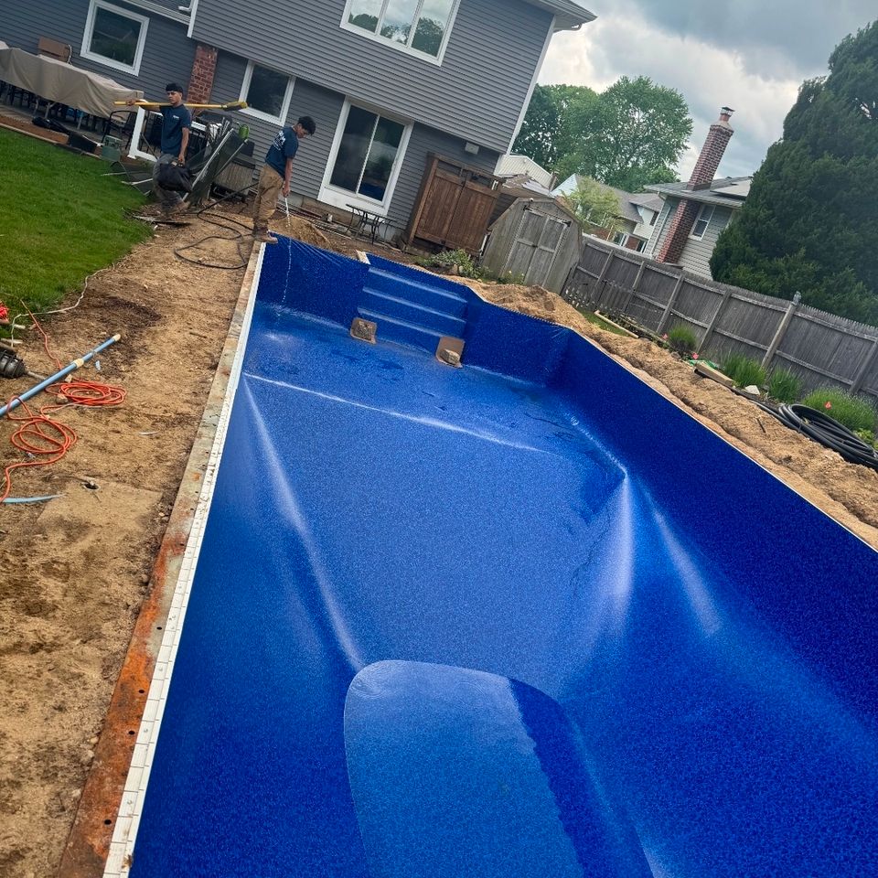 Pool crew filling a rectangular inground pool with a new liner and built-in steps in Long Island NY
