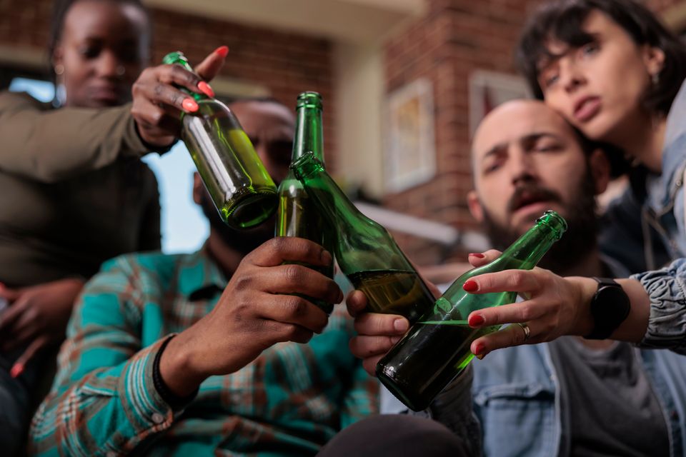 Multiethnic group friends saying cheers clinking beer bottles celebrate party event feeling happy about reunion people toasting with alcohol drinks hangout leisure activity close up