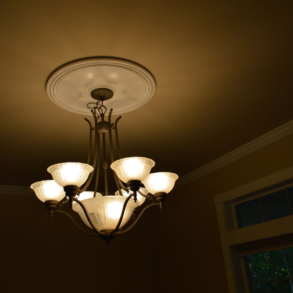 Six light chandelier with ceiling medallion and crown molding in a finished custom home dining room