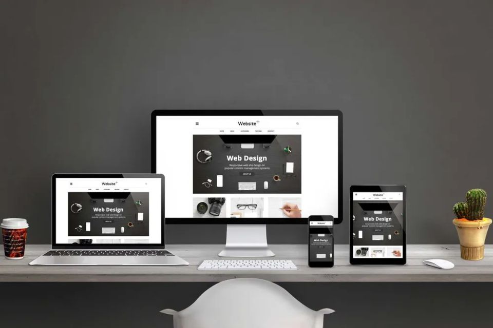 Desktop computer, laptop, tablet, and smartphone displaying a responsive business website across multiple devices.