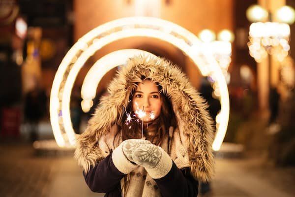 Girl with furry coat and furry gloves holding sparklers 