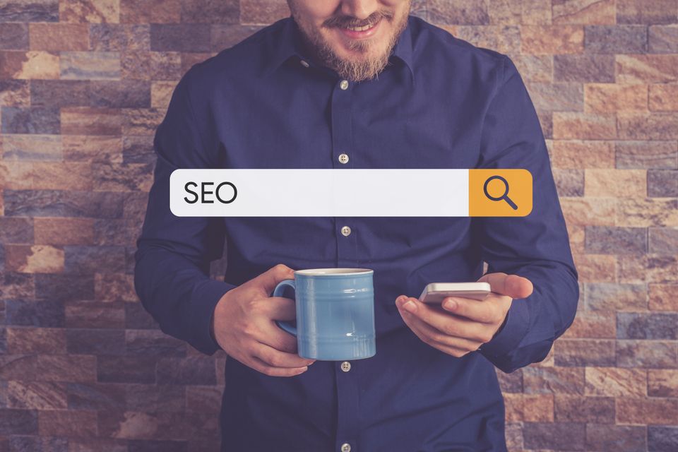 Man in blue shirt drinkning coffee and looking at phone