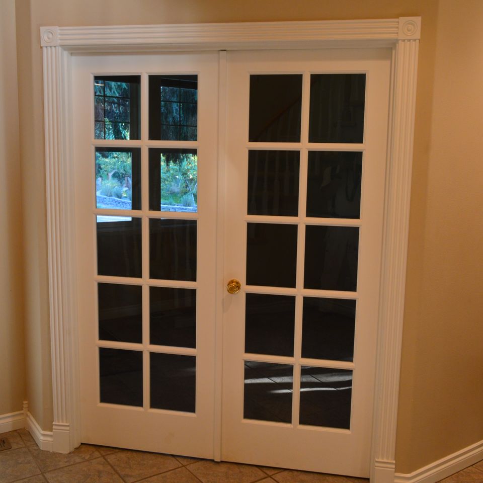 White French doors with divided glass panes and fluted casing inside a custom home