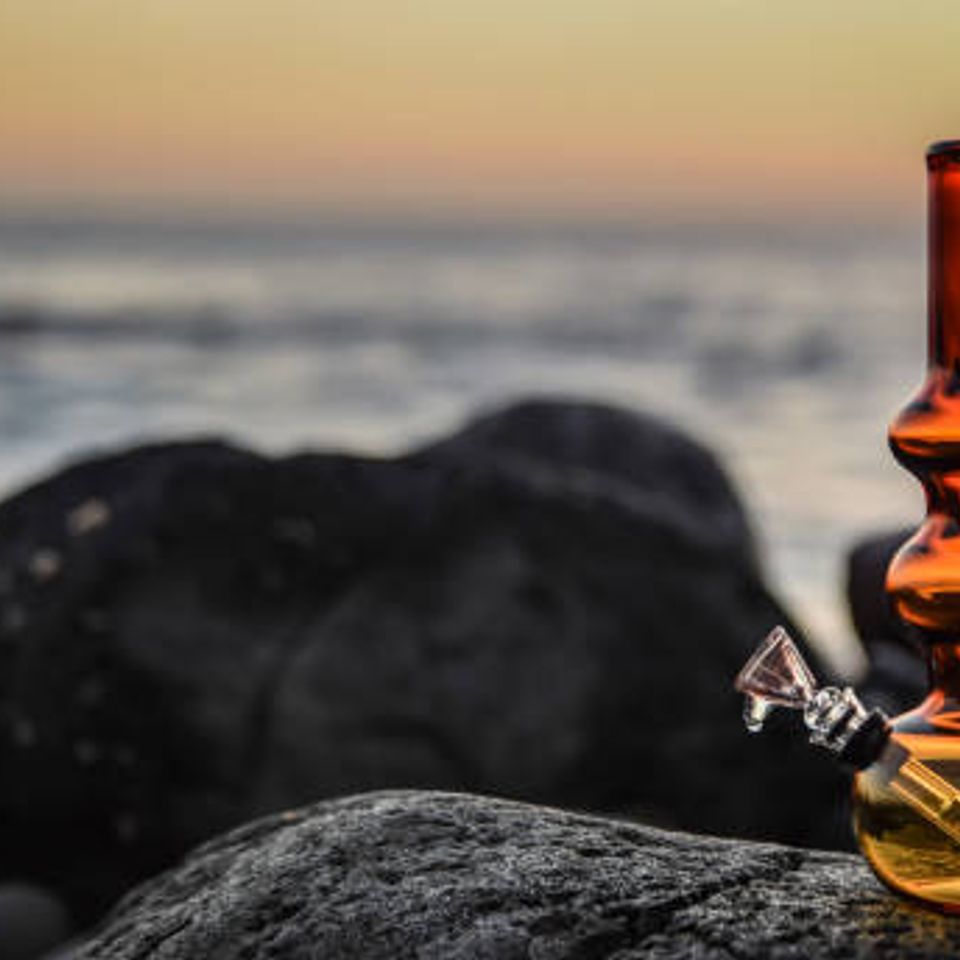 Bong resting on a rocky beach during a serene sunset.