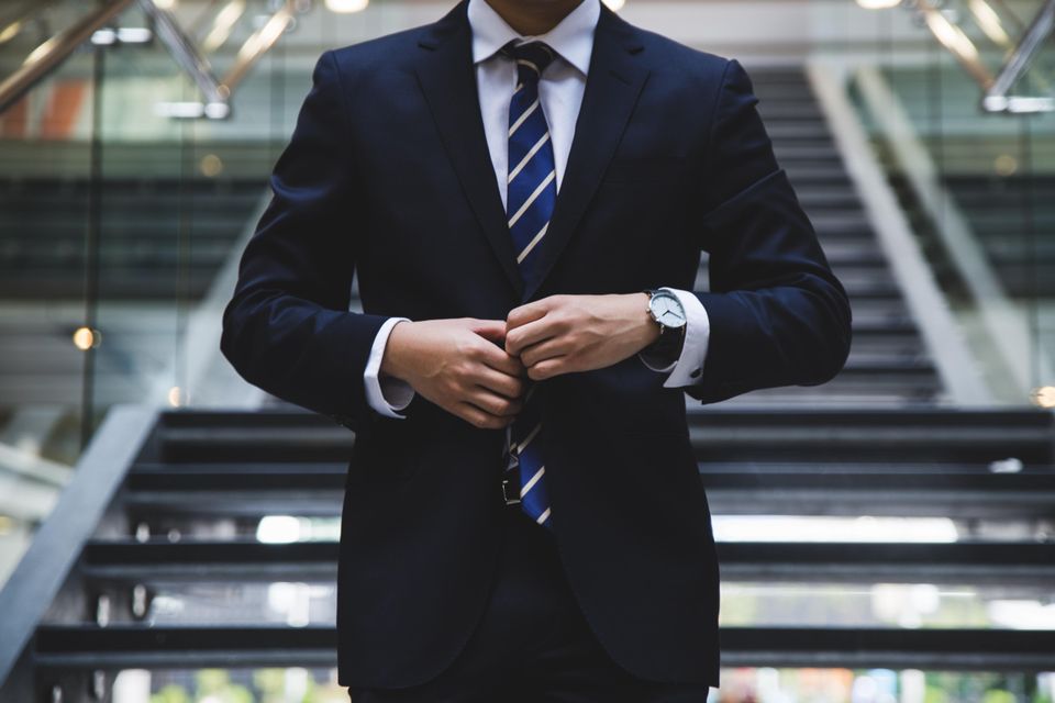business man fixing his suit for a meeting in front of a stairway