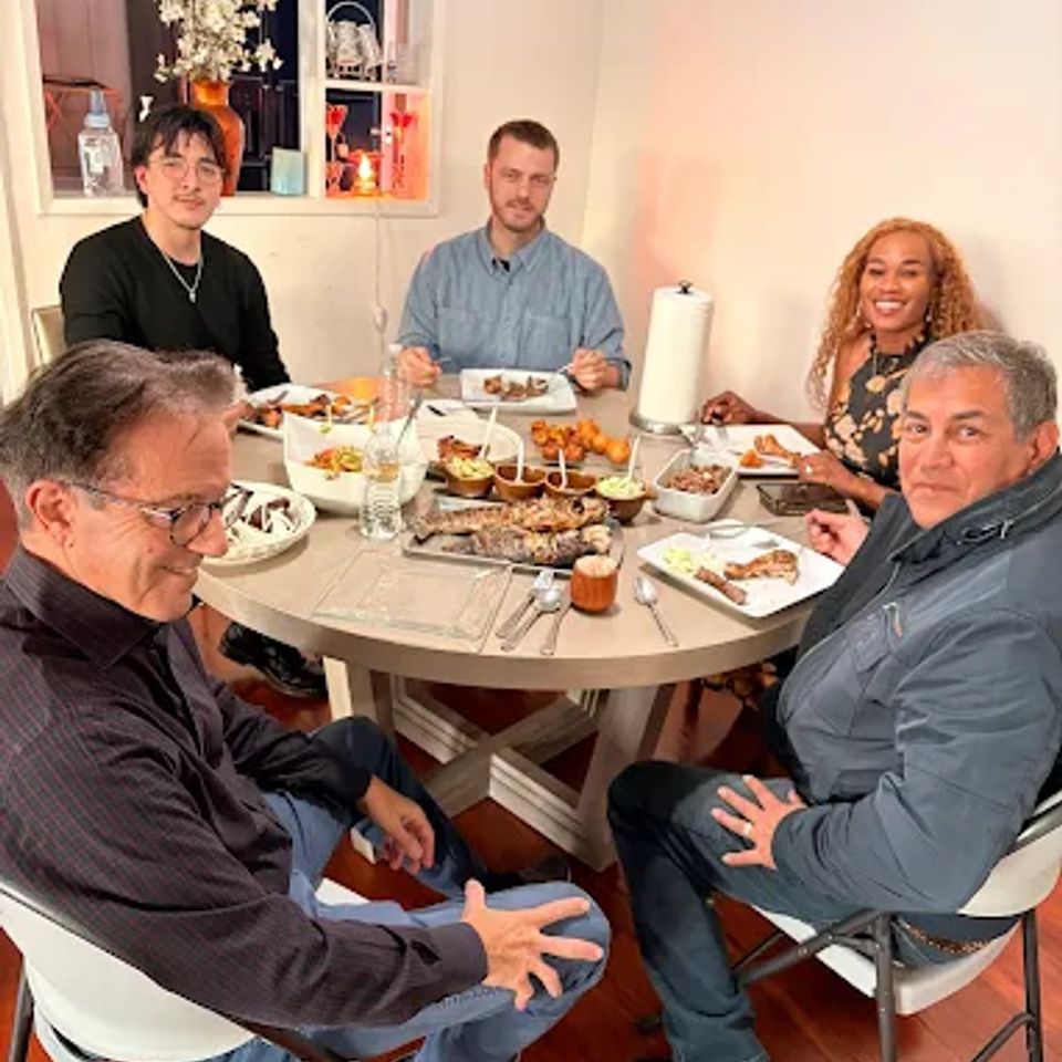 Guests sharing a home-style Cameroonian dinner around a round table in Los Angeles