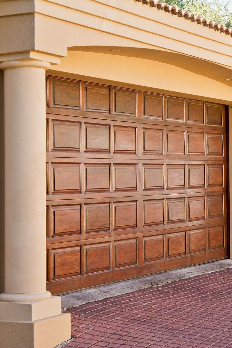 Two-story stucco home with sand-colored exterior and brown double garage doors, representing safe and well-maintained residential garage doors